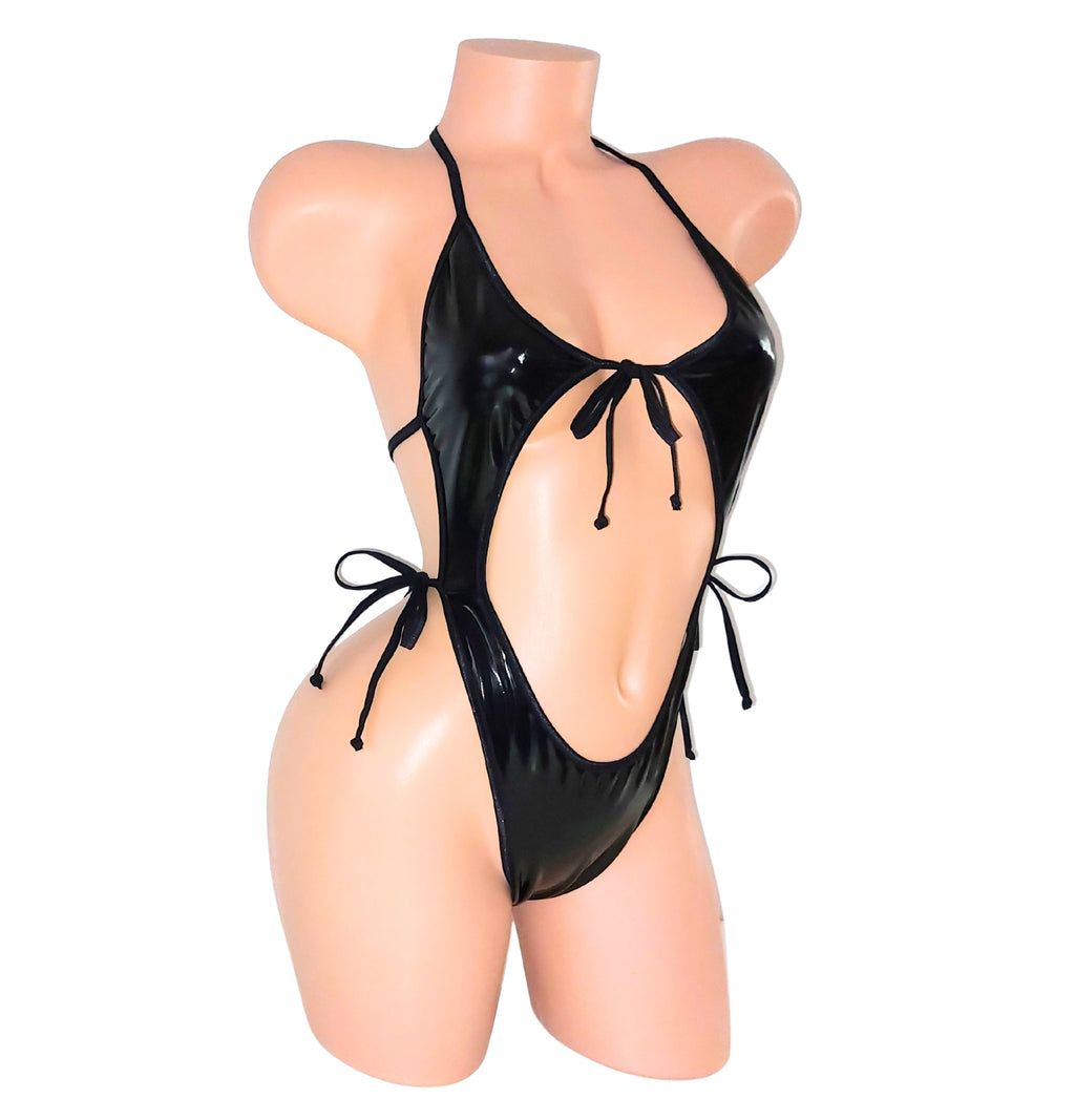 A black Vinyl wet look vinyl one piece backless leotard bodysuit on a plastic beige mannequin torso against a plain background.