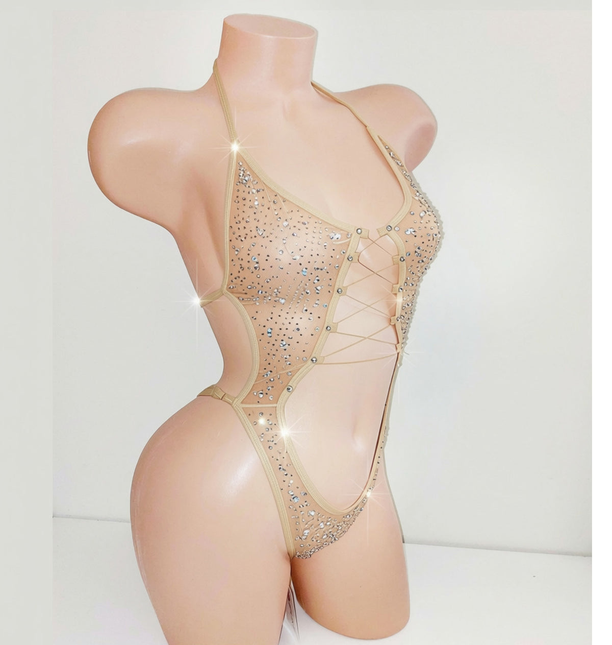 A beige mannequin displaying a beige sparkly leotard bodysuit with a center cutout and covered in rhinestones.