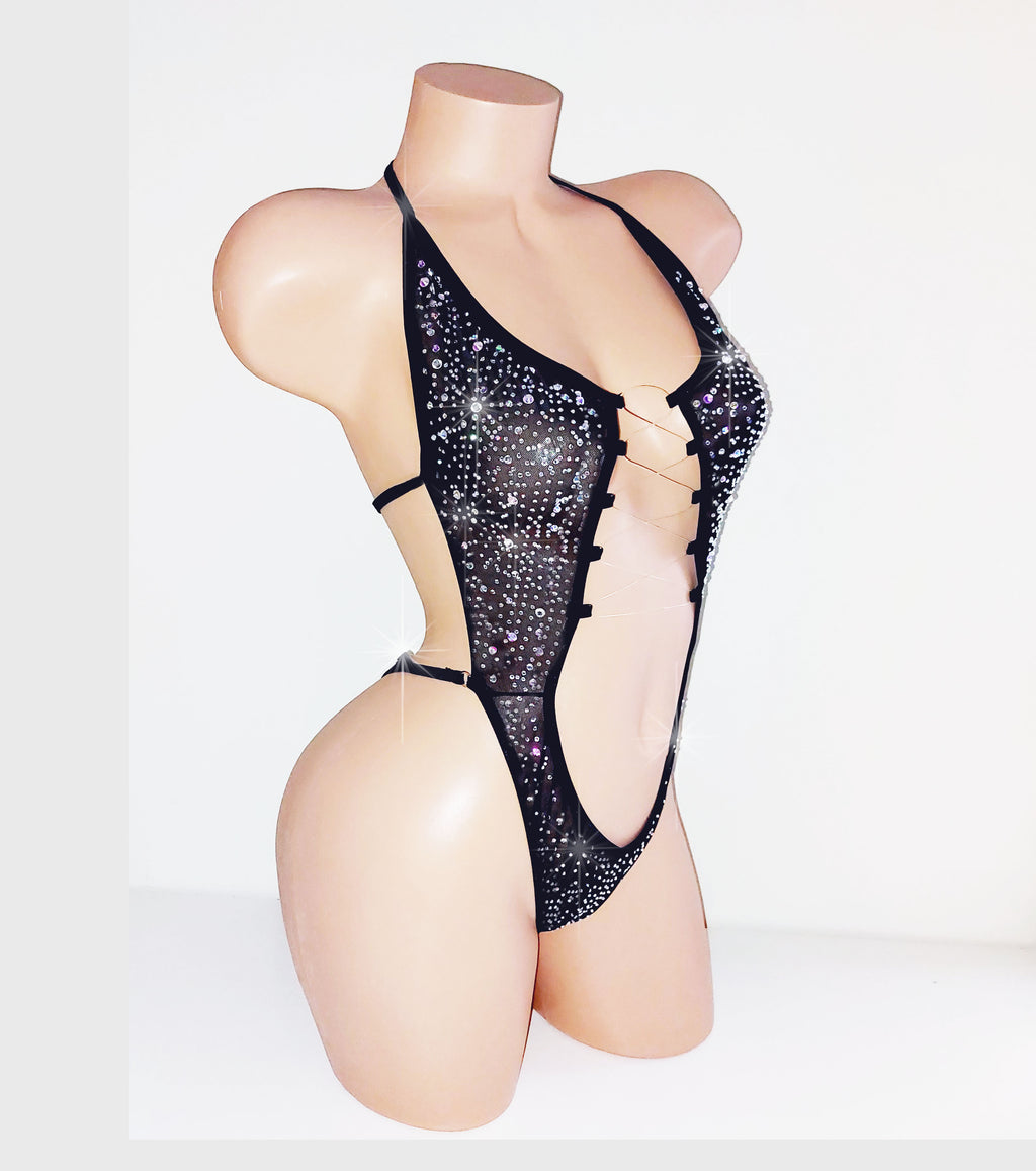 Black mesh one piece covered in rhinestones on a beige plastic mannequin torso against a plain background. 