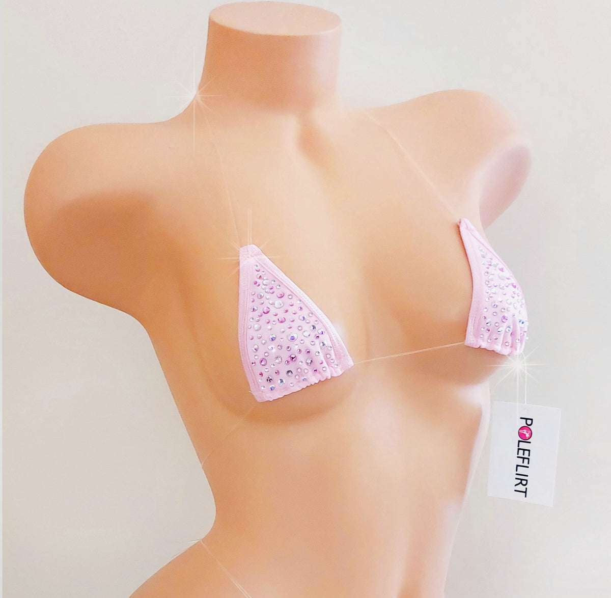 A light pink rhinestone-covered triangle bralette displayed on a beige mannequin torso, with a white 'POLEFLIRT' brand tag hanging from the side.