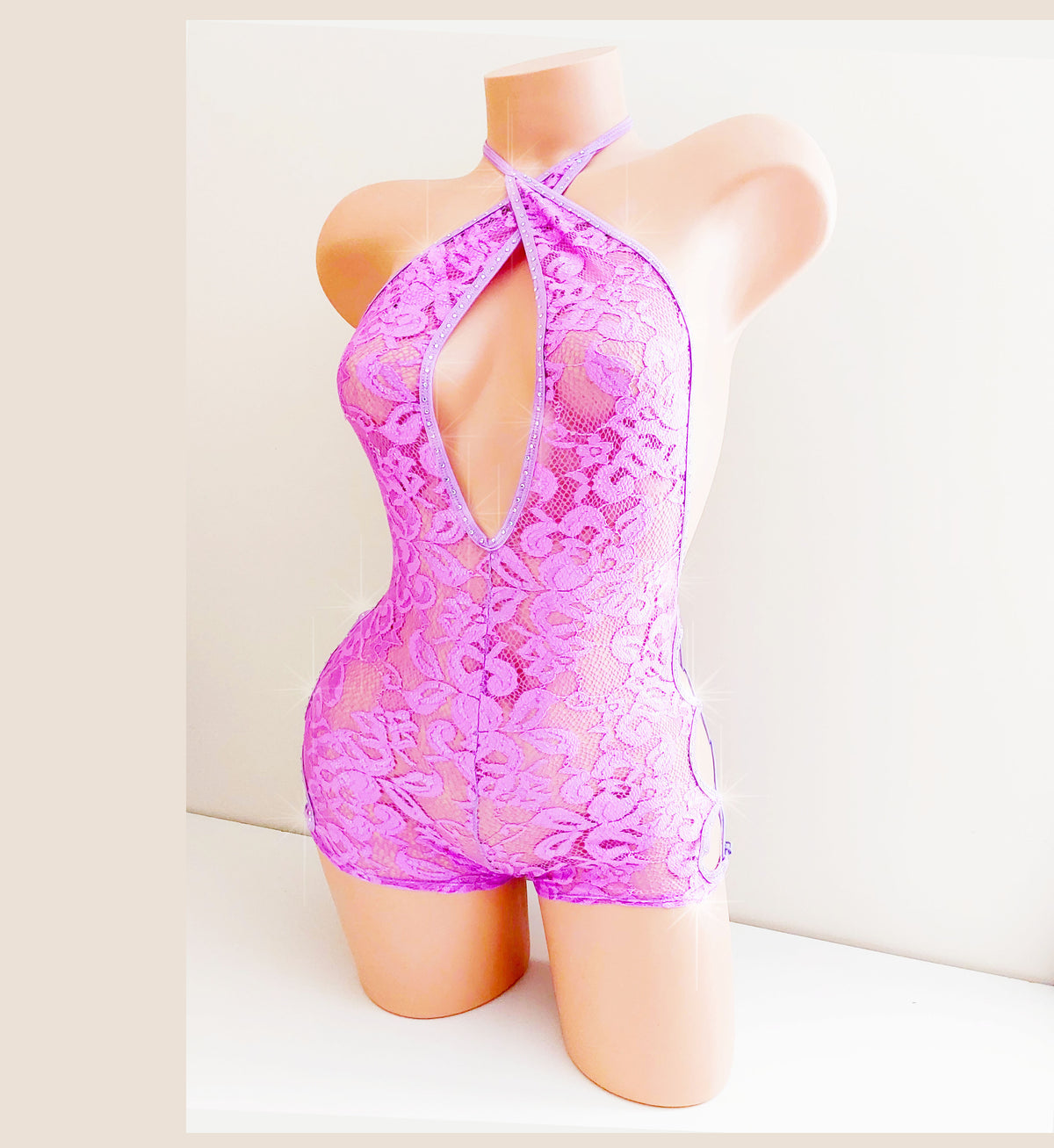 Plastic mannequin torso showing a purple lace one piece with side cord lace ups and rhinestones against a plain background.