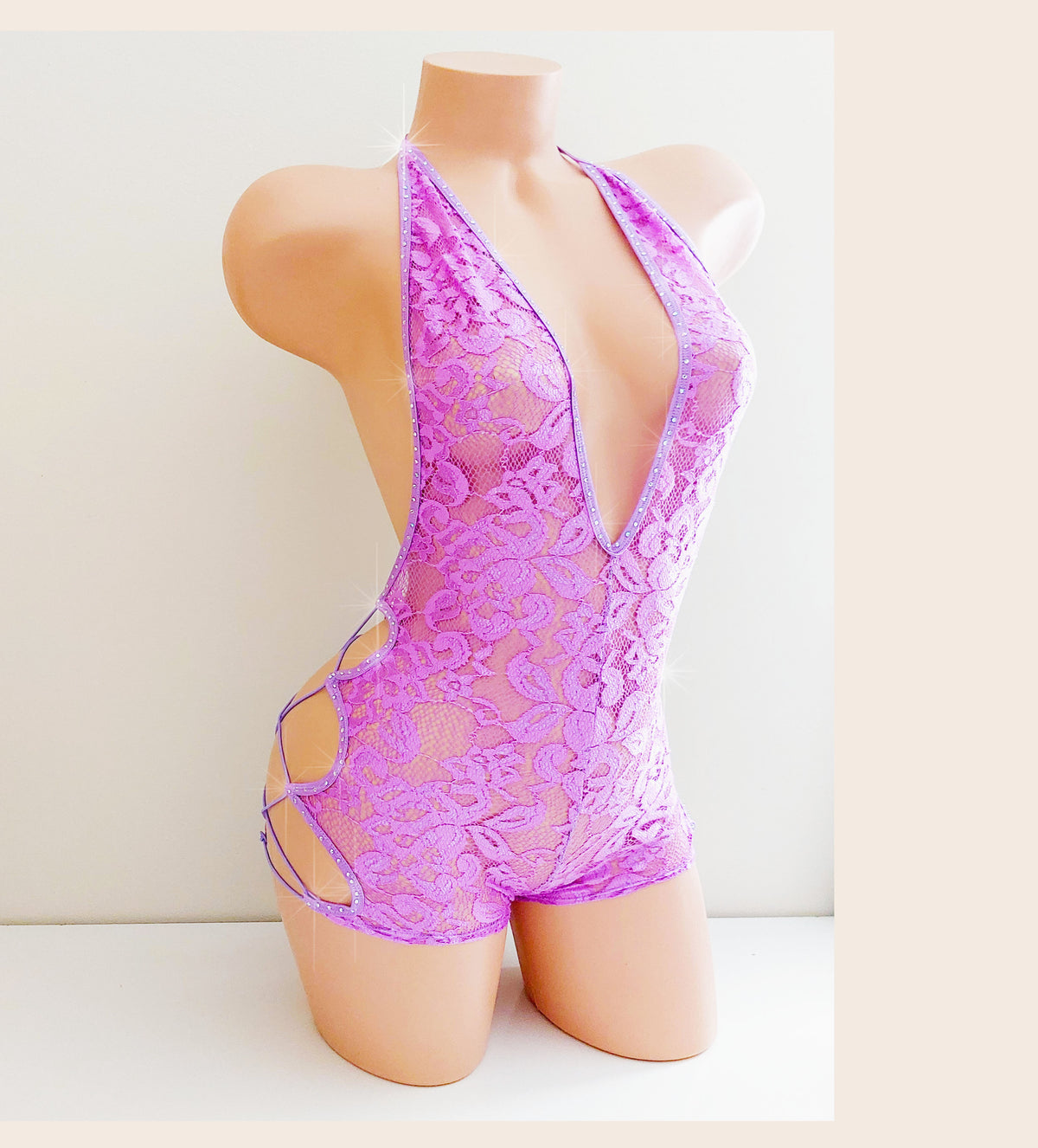 Plastic mannequin torso showing a purple lace one piece with side cord lace ups and rhinestones against a plain background.