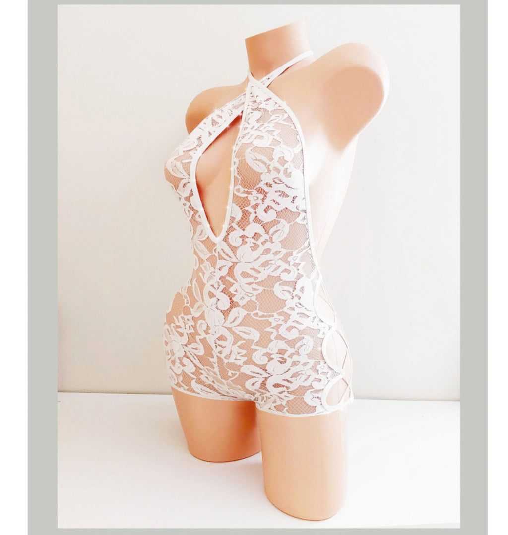 A plastic beige mannequin torso displays a cute white lace Bachelorette or Wedding outfit one piece above the knee romper with sparkle accents.