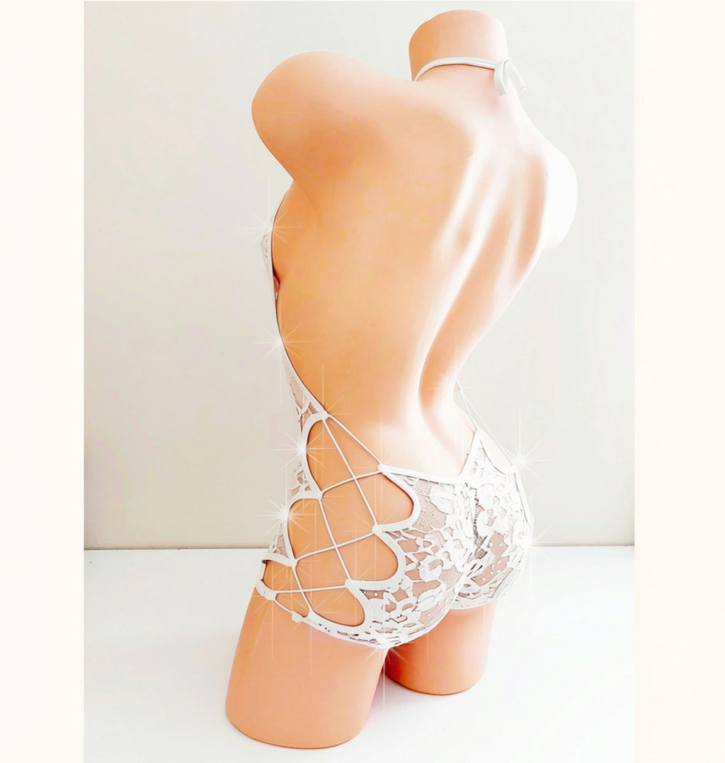 A plastic beige mannequin torso displays a cute white lace Bachelorette or Wedding outfit one piece above the knee romper with sparkle accents.