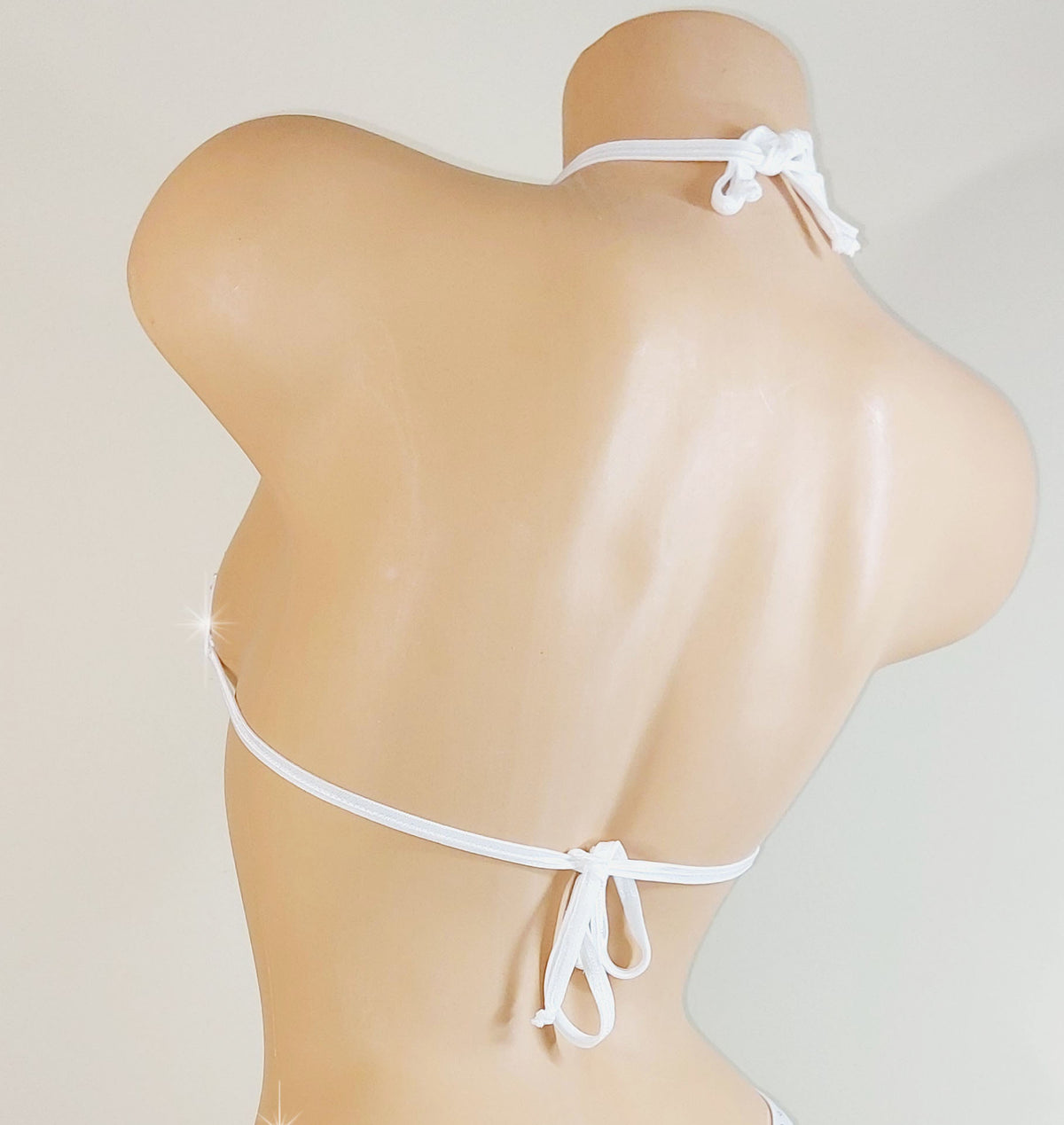 White bedazzled rhinestone bikini top with thin straps on a mannequin against a light gray background