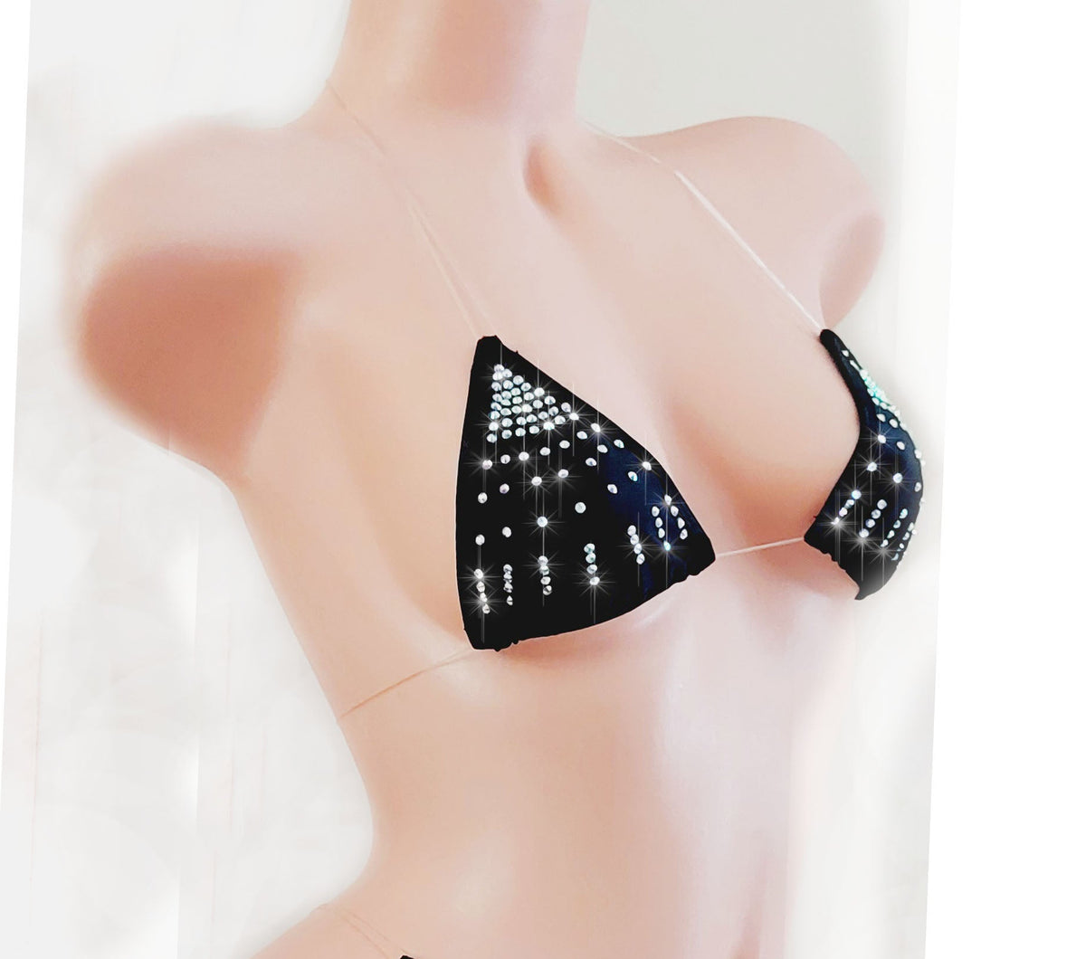 Black rhinestone bikini top with clear elastic straps that are transparent on a model against a plain backdrop.