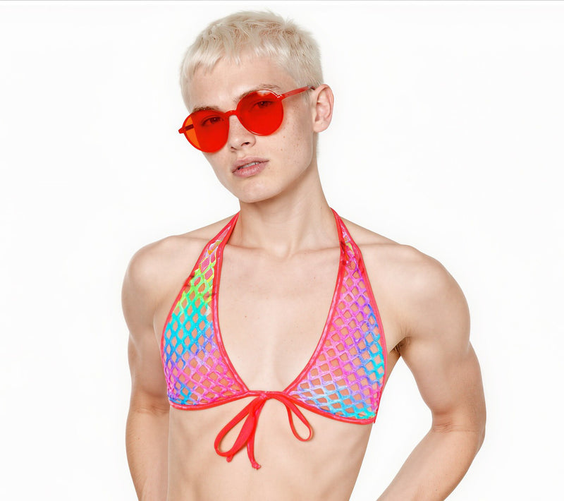 A blonde man wearing a rainbow fishnet halter top and red heart shaped sunglasses posing against a white background.