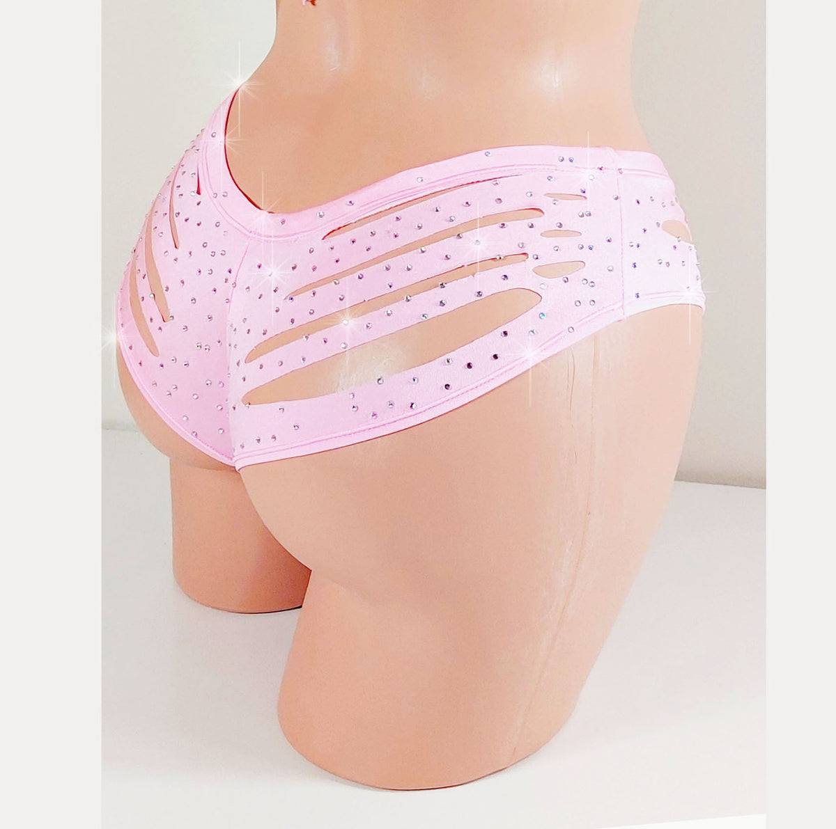 Mannequin wearing pink boyshorts with cut-out design and scattered rhinestones all over on a plain background