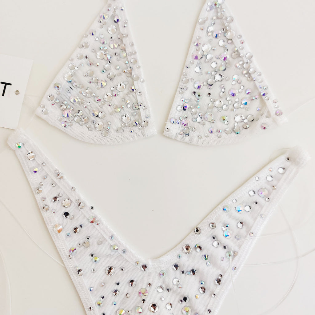 White bikini-style lingerie pieces covered with iridescent rhinestones, arranged on a light neutral background.