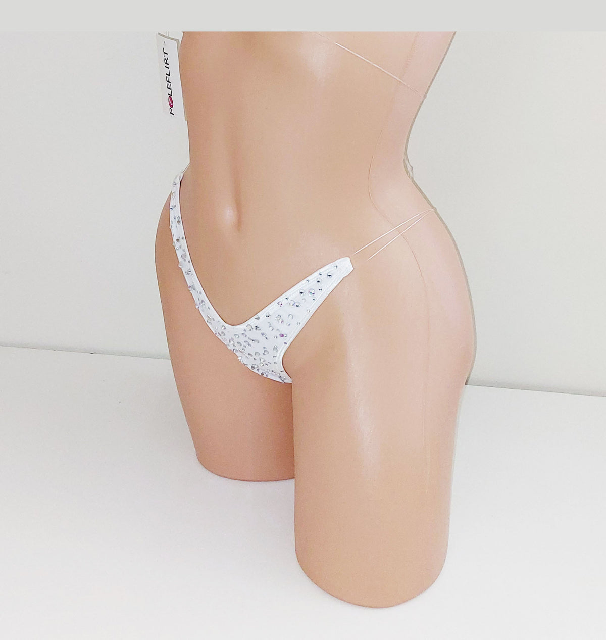 White thong-style underwear covered in  bedzzled crystal gem rhinestonest, displayed on a beige mannequin torso against a plain white background.