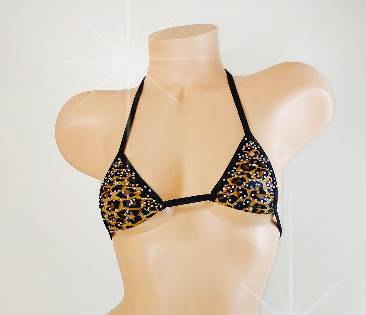 A triangle bikini top displayed on a beige mannequin torso against a light gray background. The bikini top features a black and gold leopard print pattern with rhinestone embellishments and thin black straps.
