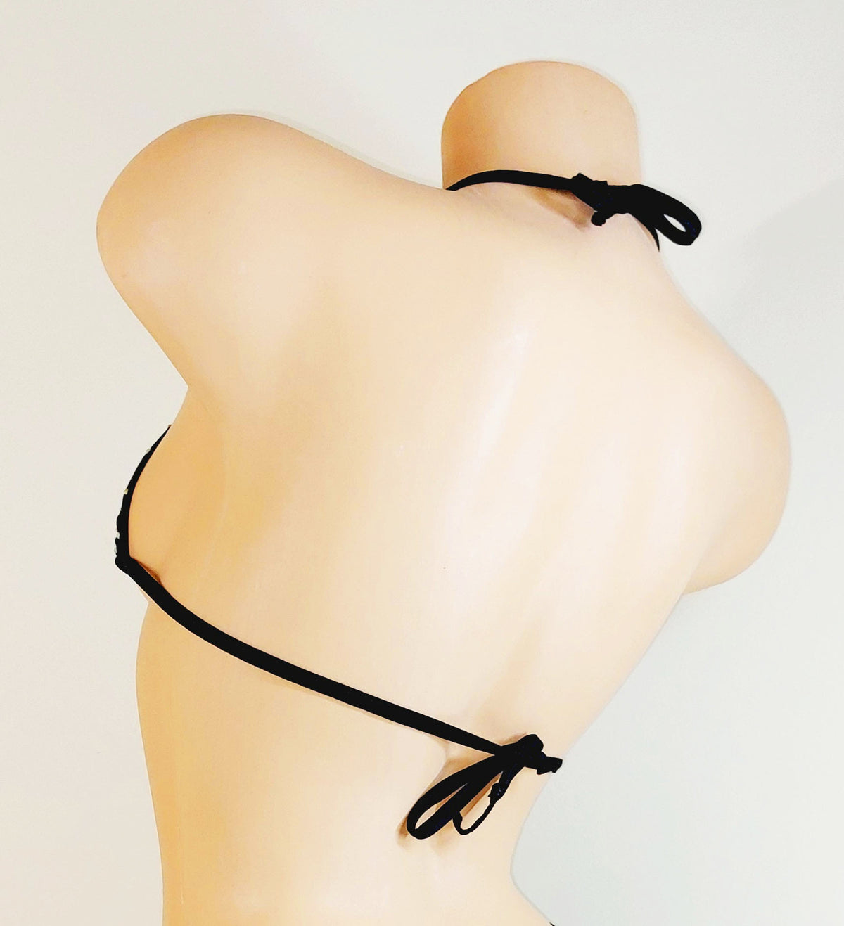 Back view of a black bikini top on a mannequin with a plain background