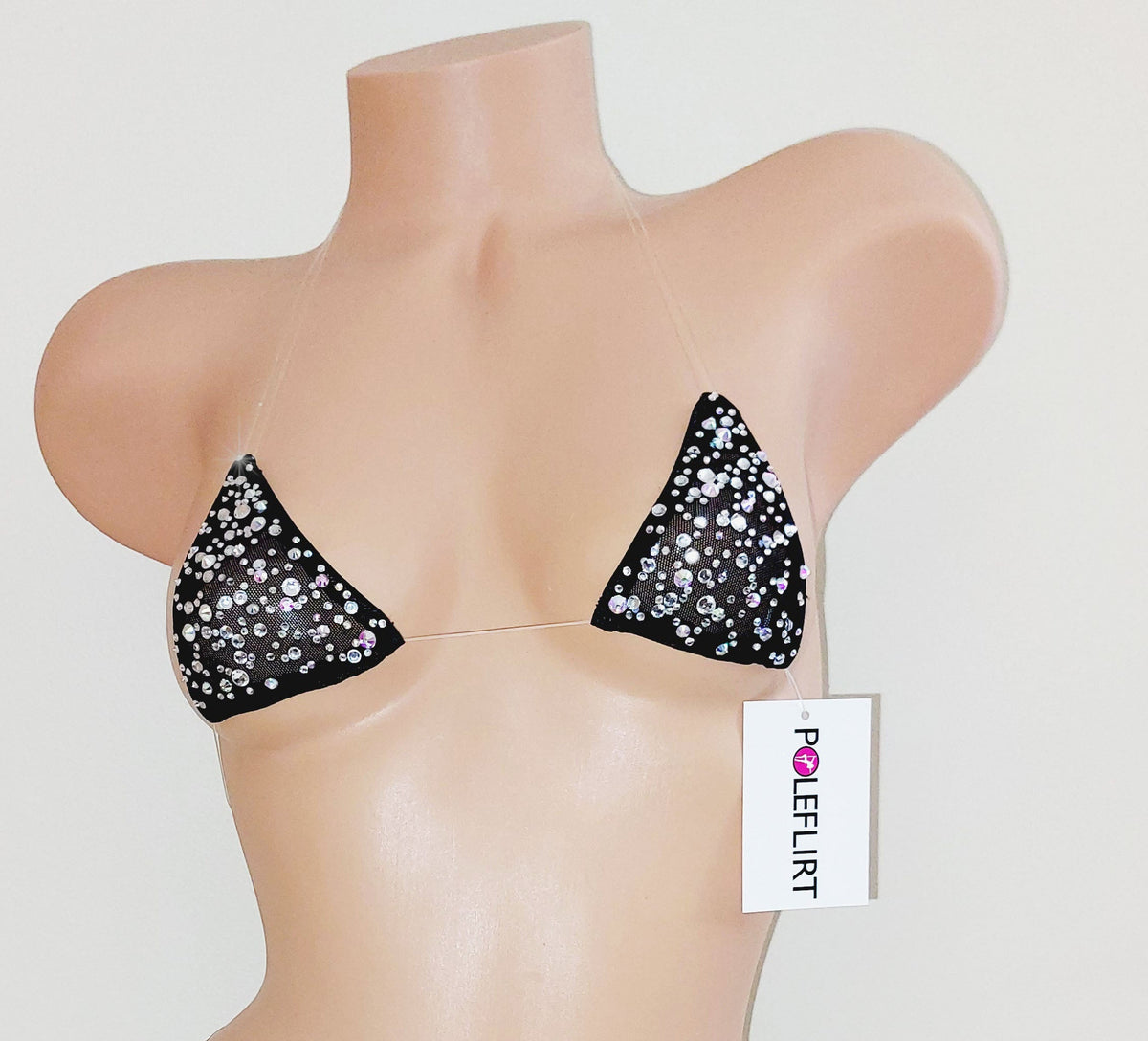 Lots of sparkling rhinestones  on a tiny micro bikini top with clear straps with a hang tag reading POLEFLIRT on a plastic beige mannequin torso on a plain background.