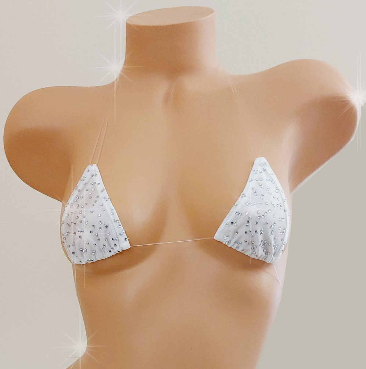 White skimpy bikini with rhinestones and invisible clear elastic straps on a mannequin torso against a blank background.