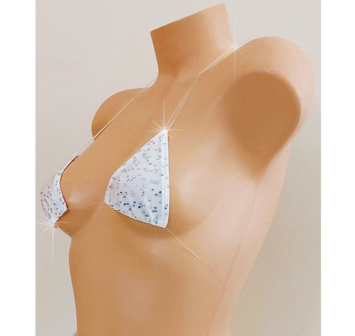 White skimpy bikini with rhinestones and invisible clear elastic straps on a mannequin torso against a blank background.