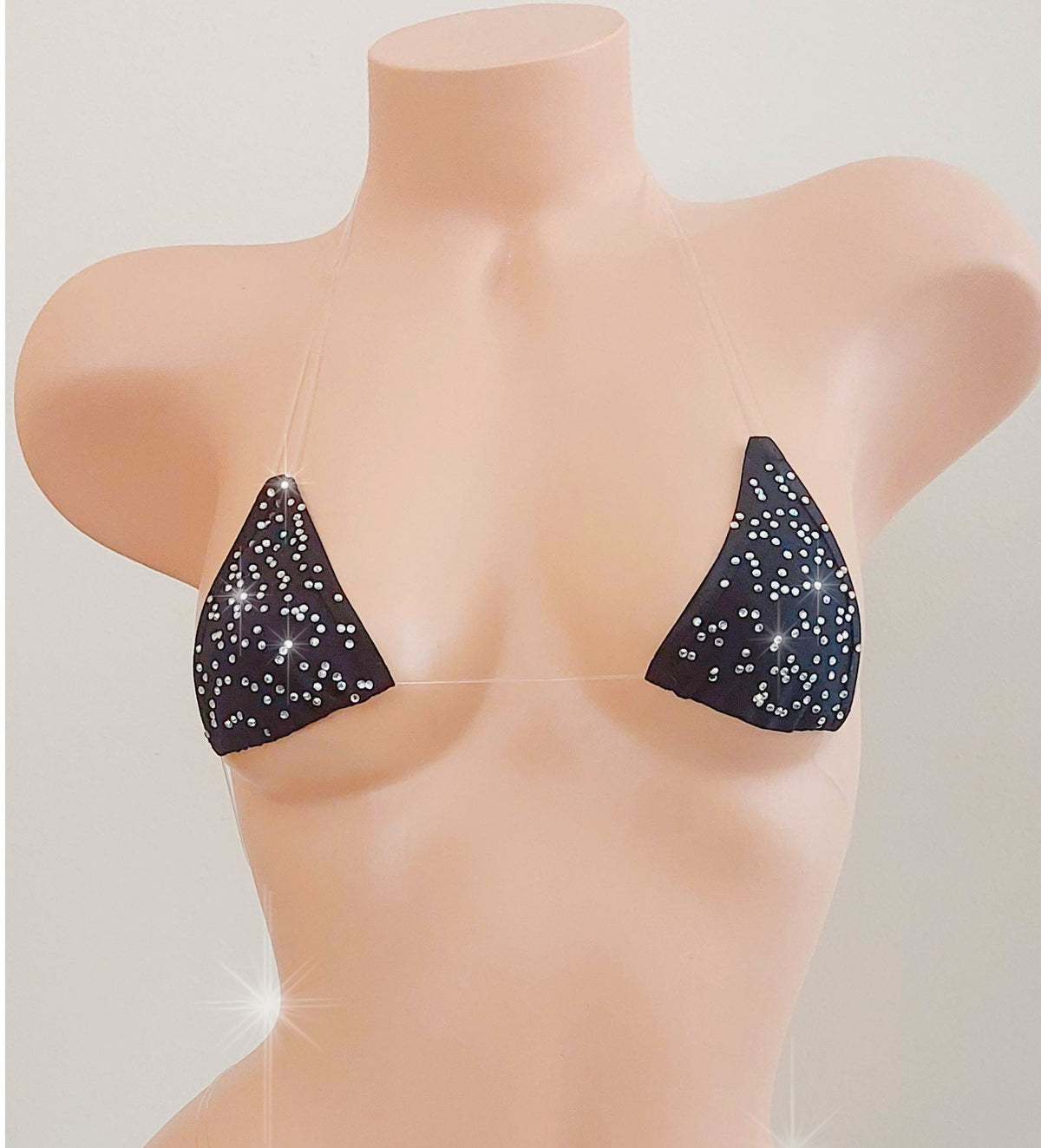 Black invisible straps micro bikini covered in rhinestones on a torso mannequin on a white background.