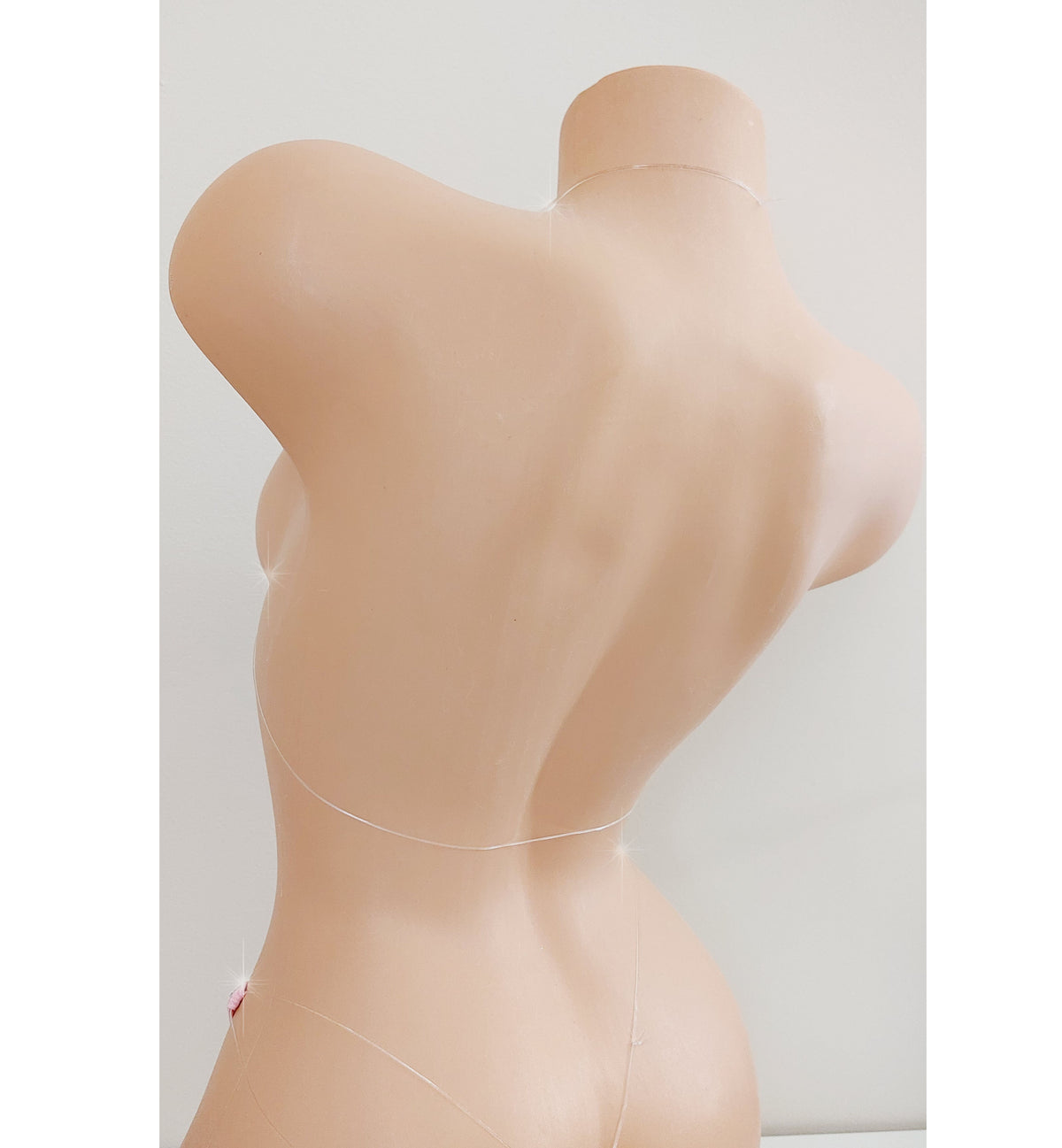Rear view of a clear strap bikini on a plastic beige mannequin torso. The clear straps appear invisible on the mannequin.