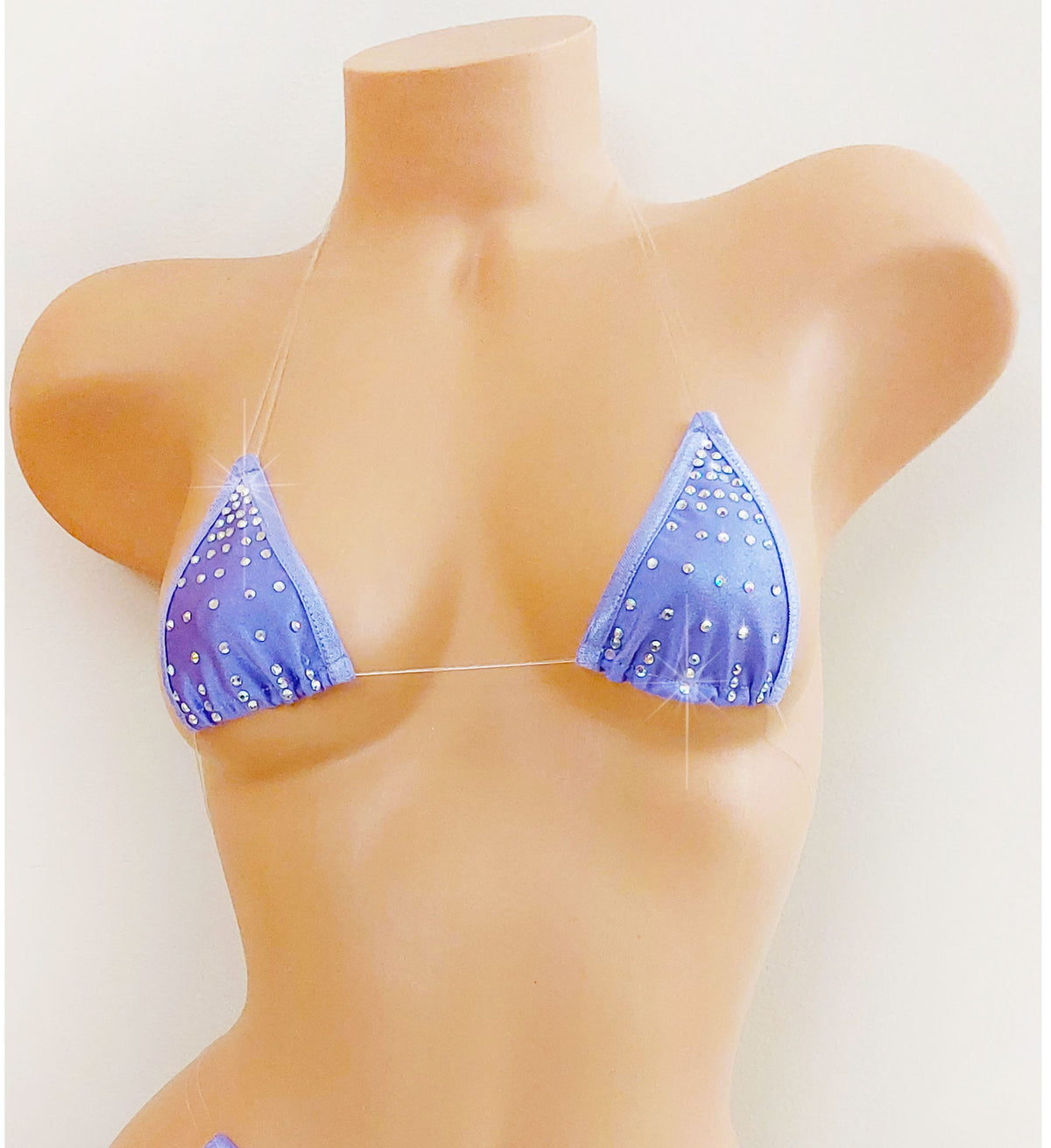 Lavender rhinestone design triangle bikini top with clear straps that appear invisible on a beige plastic female torso mannequin against a plain background.