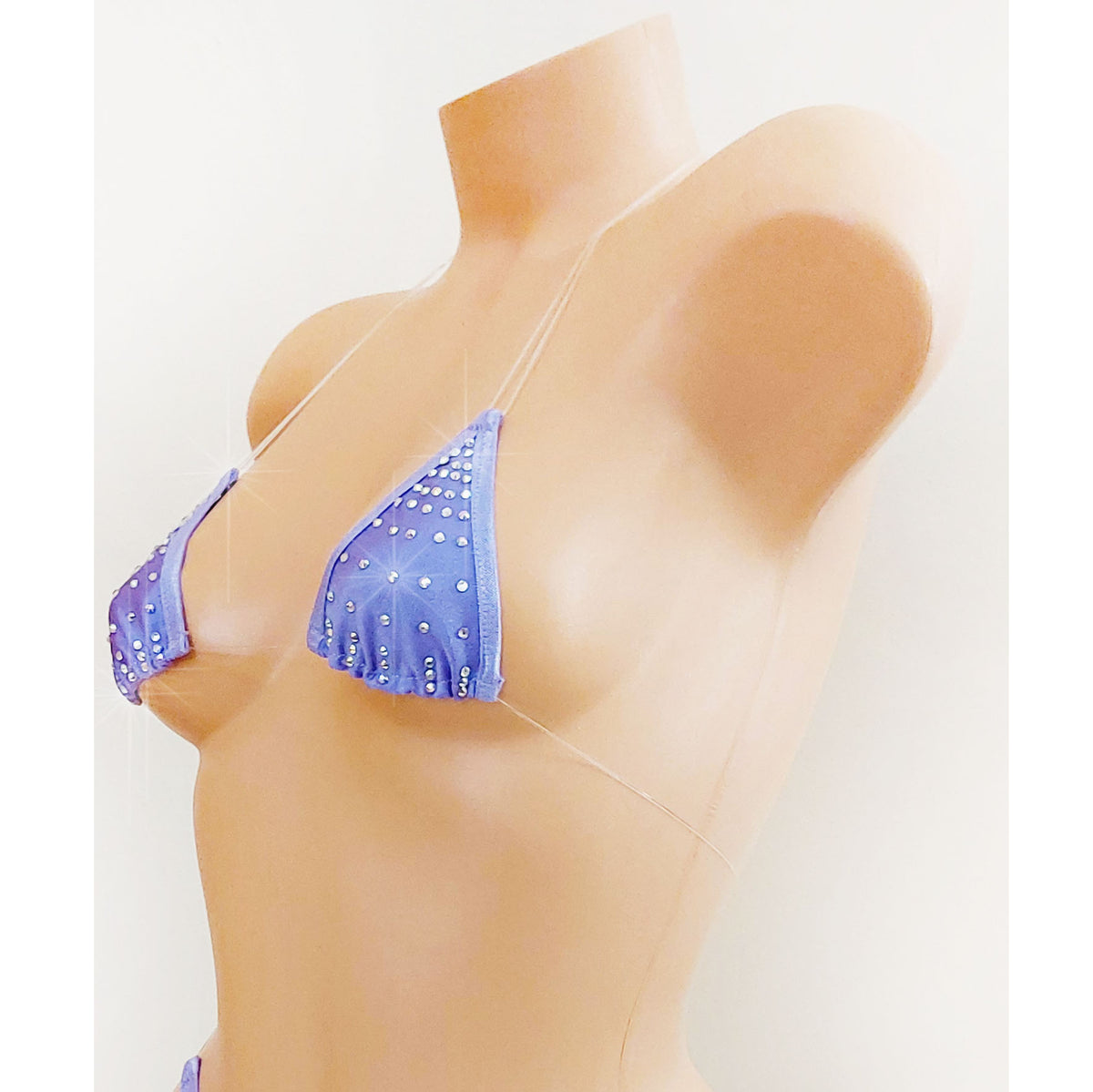 Side view of a Lavender rhinestone design triangle bikini top with clear straps that appear invisible on a beige plastic female torso mannequin against a plain background.