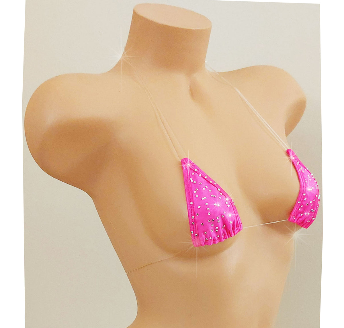 Slightly to the side view of a Hot PInk rhinestone bikini top with clear elastic cord straps that appear invisible on a torso mannequin on a white background.