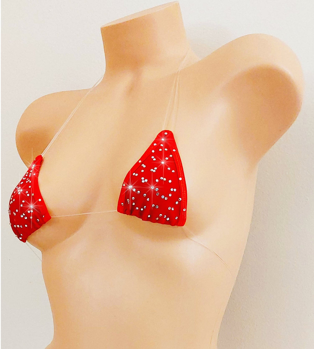 Red bikini set with rhinestones all over and clear elastic straps, displayed on a beige female mannequin torso against a plain light background.
