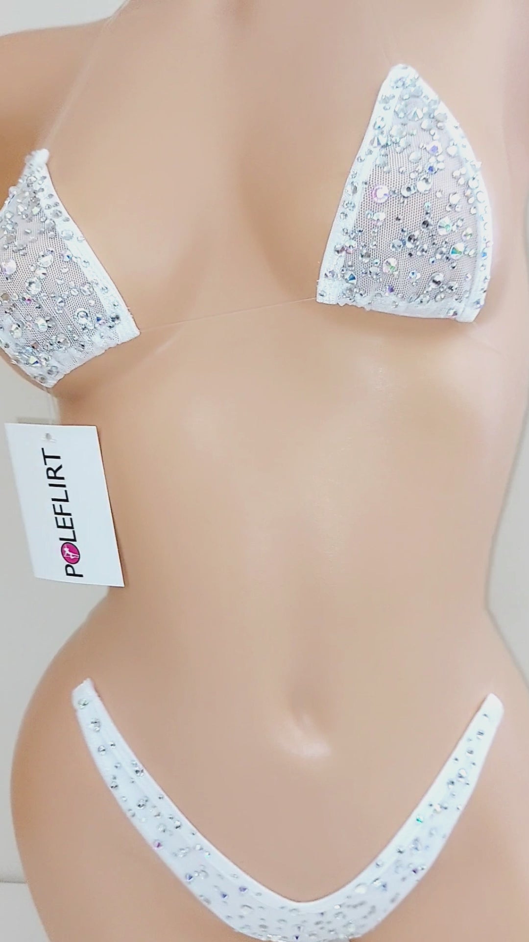 Video of a close up beige mannequin torso displaying a rhinestone covered minimal coverage bikini with clear elatic straps that appear invisible.