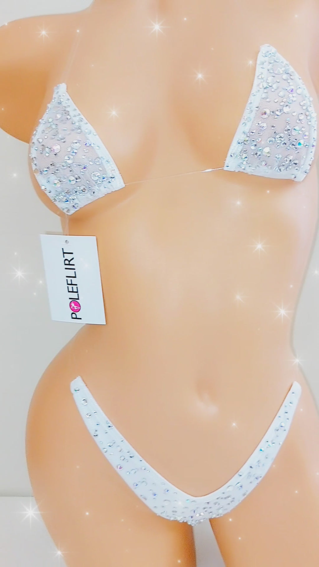 Video of a beige mannequin displaying several colors of a minimal coverage bedazzled clear elastic string bikini.